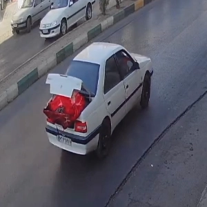 خودرو پژو سفید با پلاک نامشخص در حال حمل محمولهای در صندوق عقب